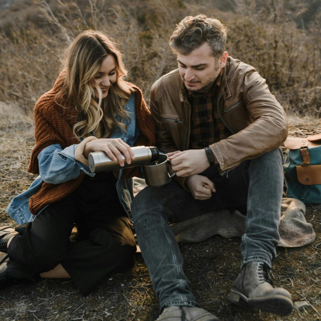 a couple of hikers having a drink from a thermal bottle