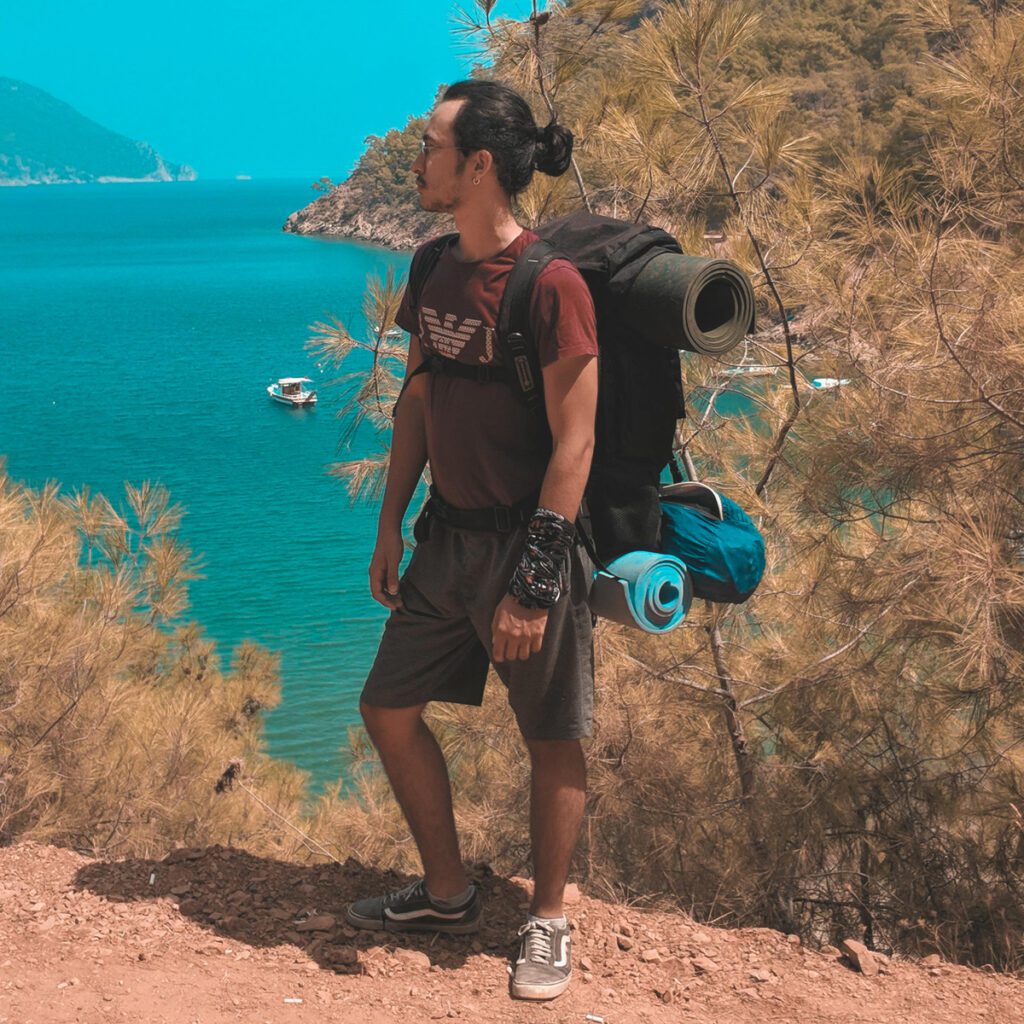 A man carrying his camping gear on a summer trip