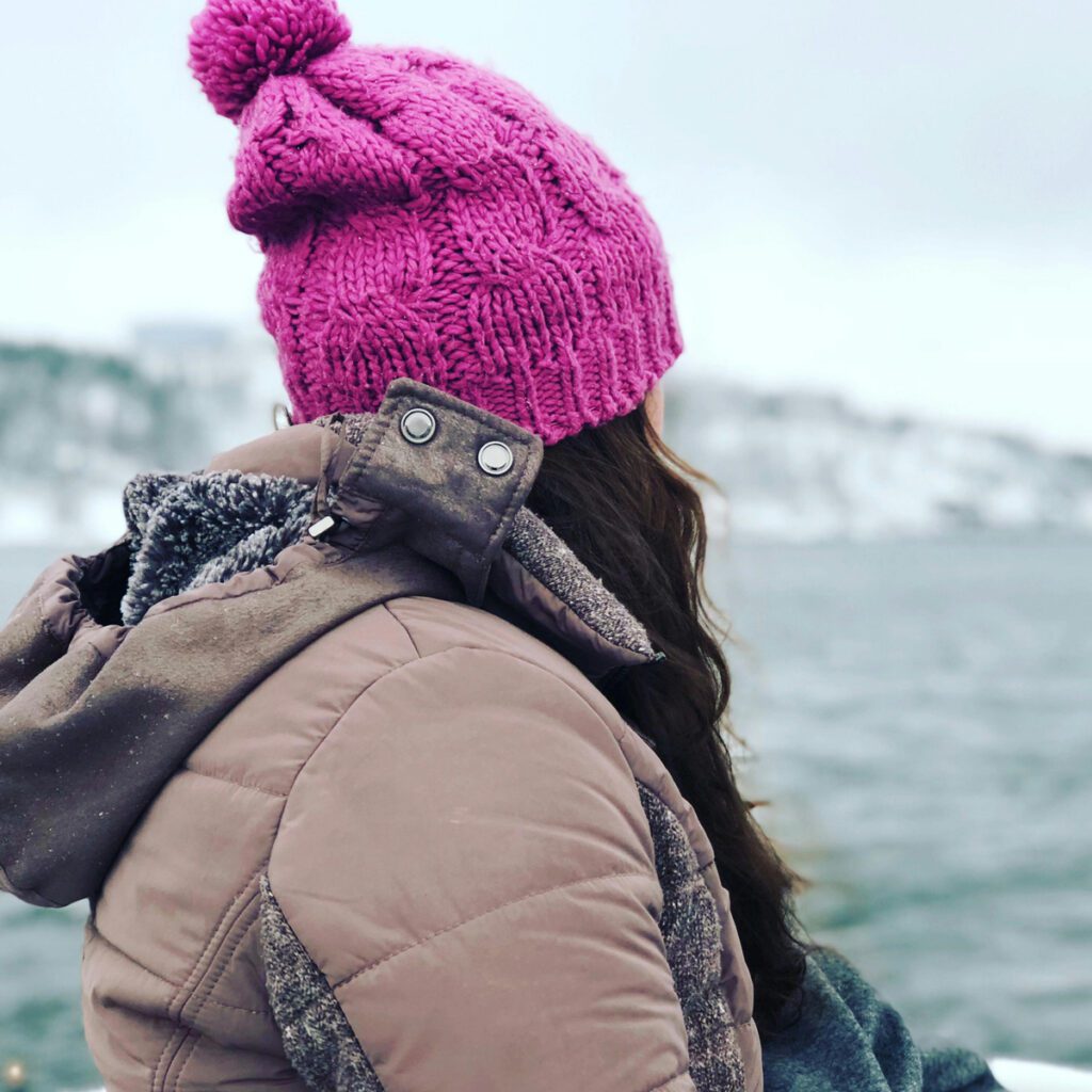 a lady wearing a beanie on a cold day by the beach