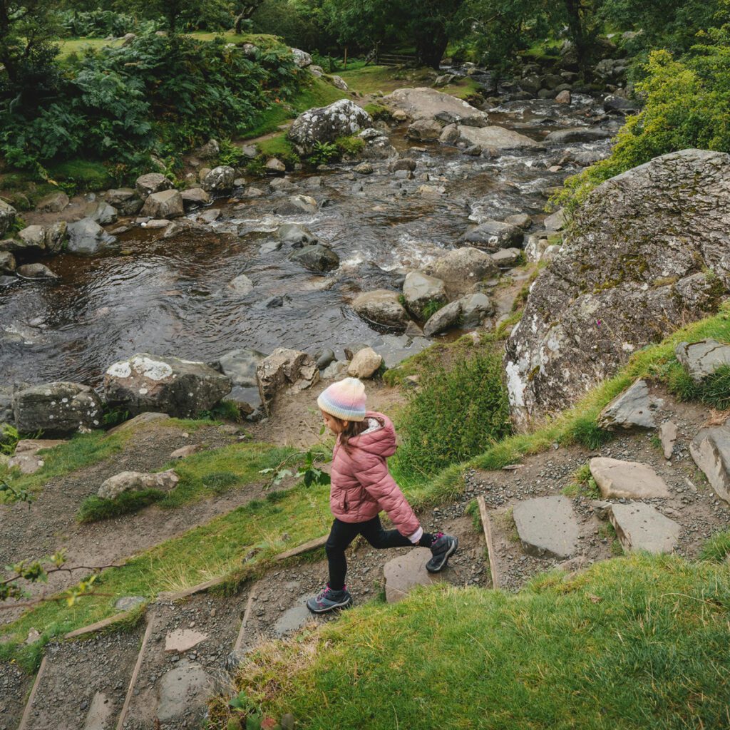 a kid walking on a trail close to a river