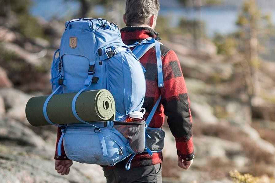 Man with a sleeping pad packed on his backpack.