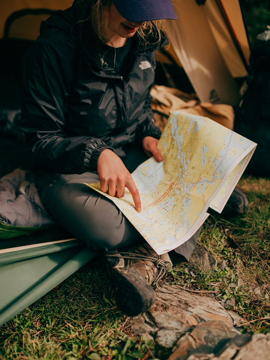 girl woman in thent camping pointing on map