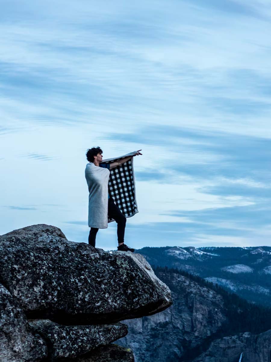 man on cliff with blanket