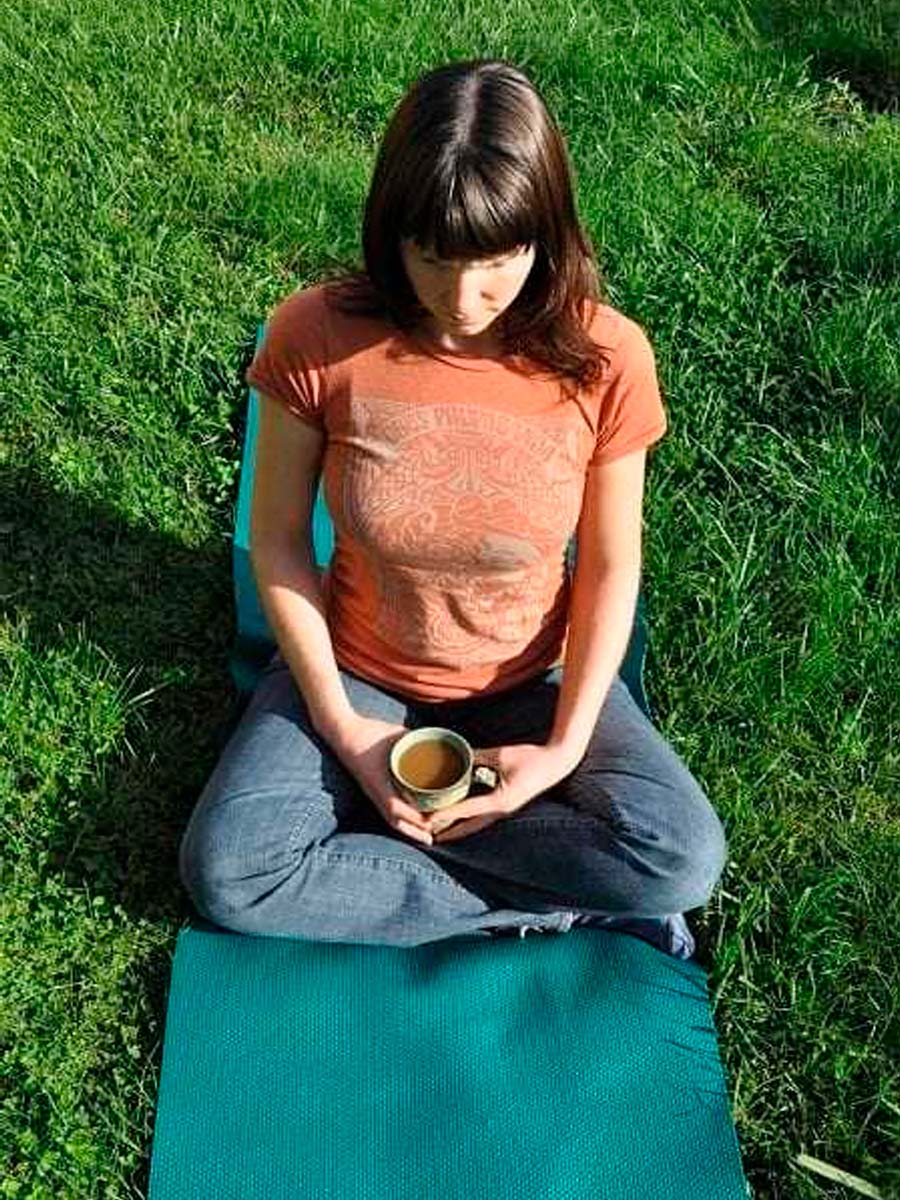 Woman meditating with a tea in her hands.