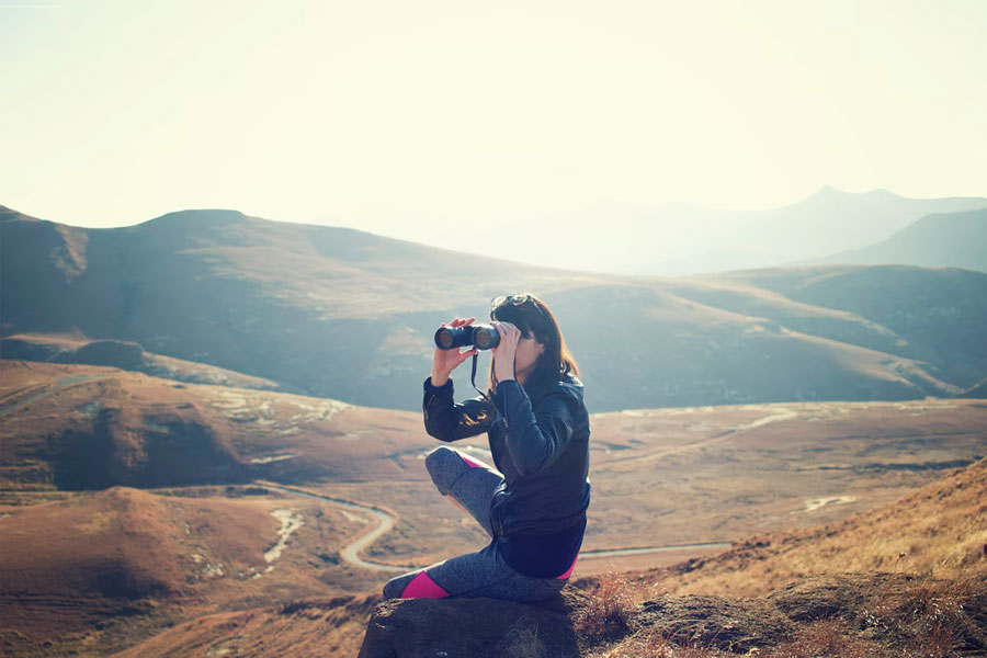 woman using binoculars hikign