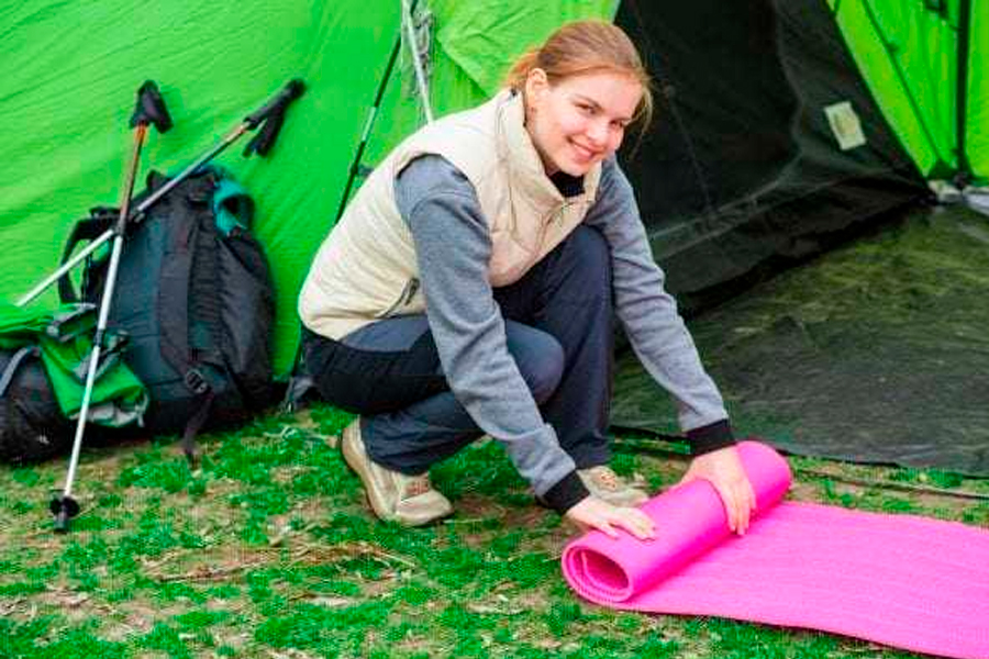 Woman rolling up a sleeping pad.