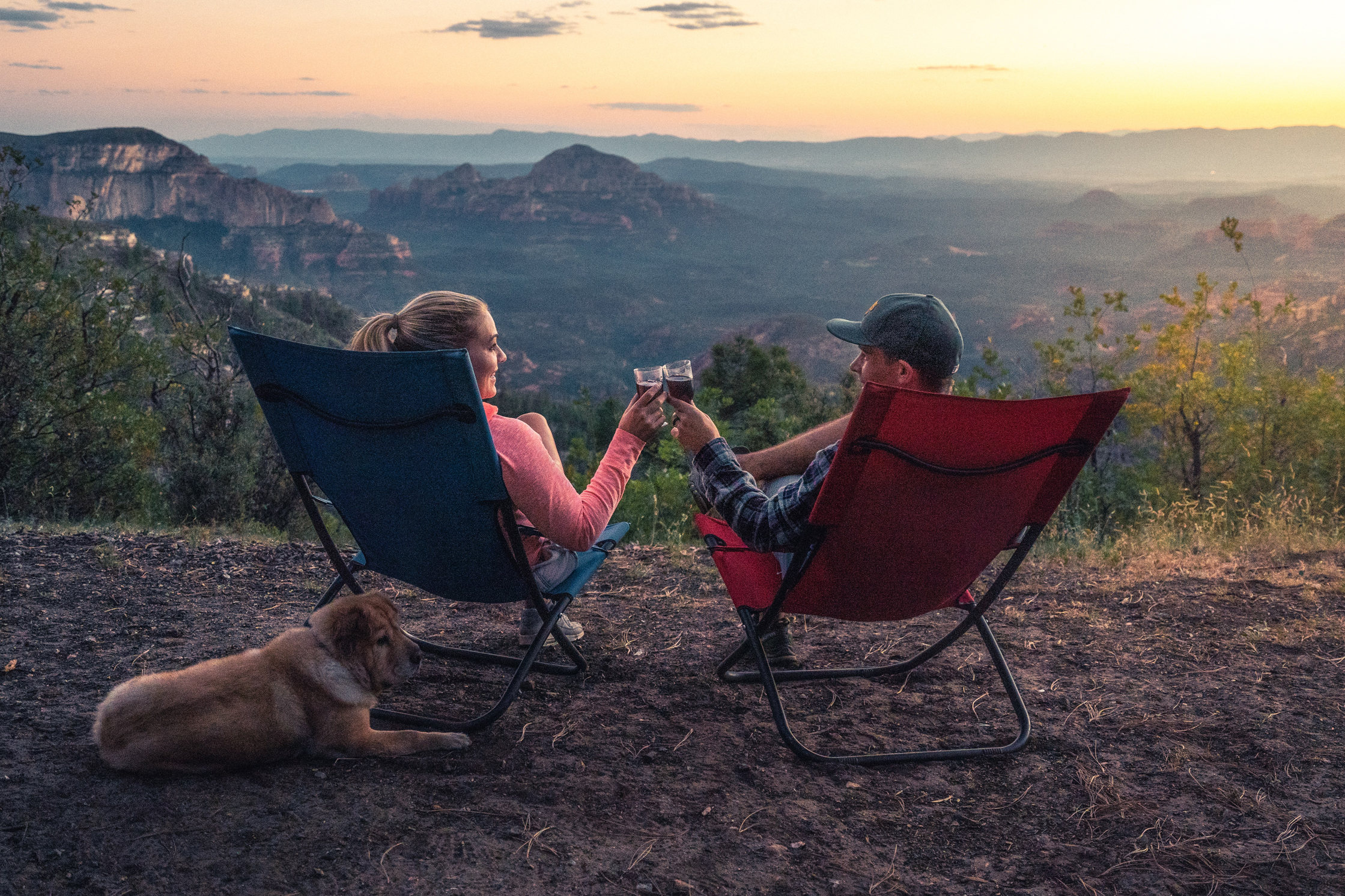 a couple sitting on camping chairs and having a toast