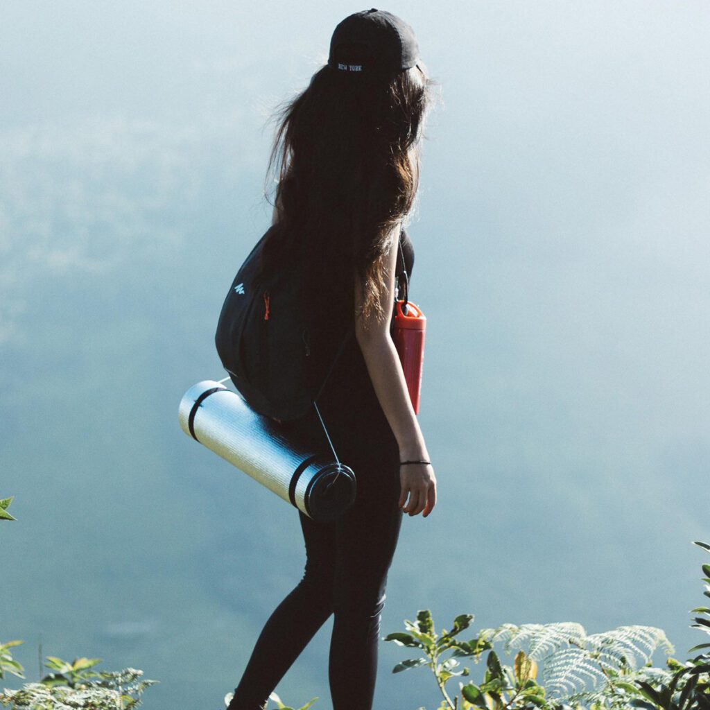 A woman carrying a backpack with a strapped sleeping pad on her back