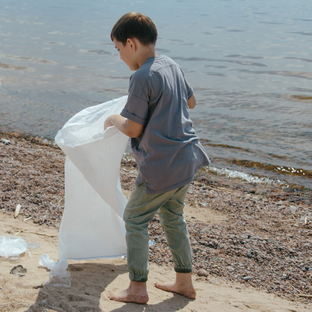 A kid picking some trash on the beach