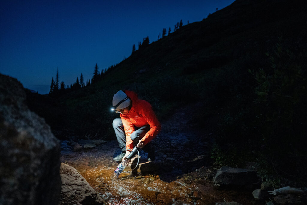 A man filtering water from a creek