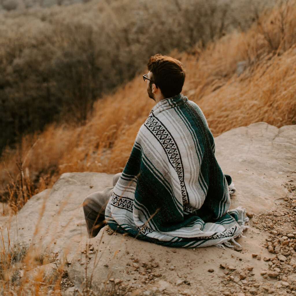 A man with an outdoor blanket over him