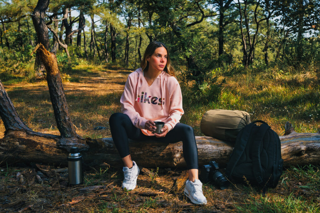Woman sitting on a log - Camping Gear for Woman