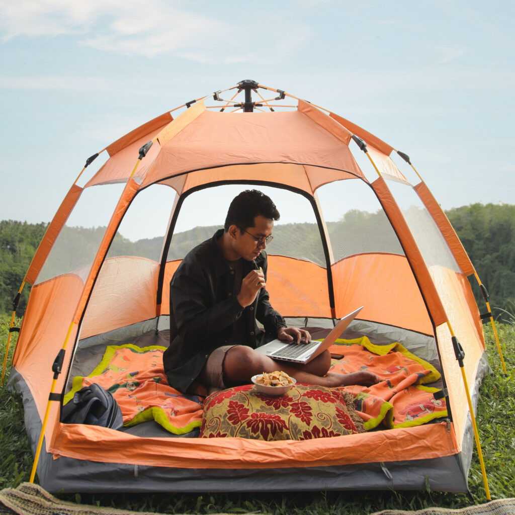 man working on his laptop while in a tent