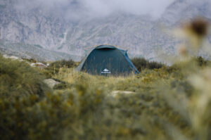 A tent pitched on a grassy area on a mountain