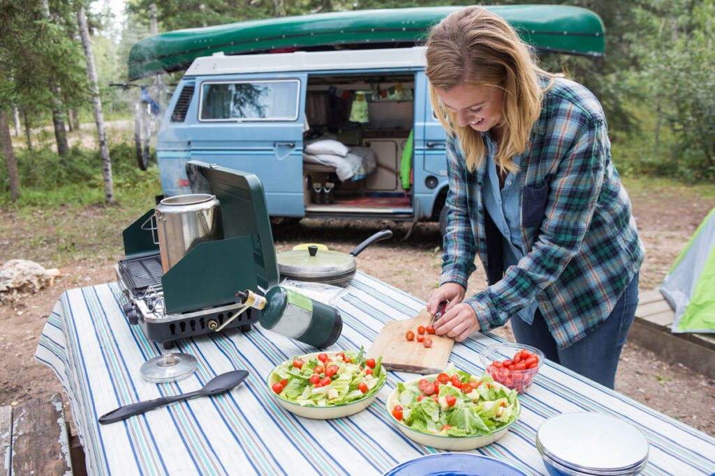 A lady slicing veggies on a table outdoors