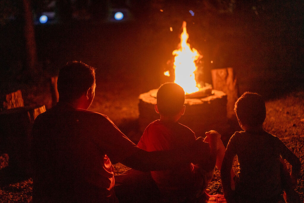 A father and his kids seated before a campfire