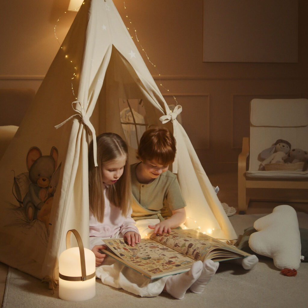 Two kids reading a book in a tent