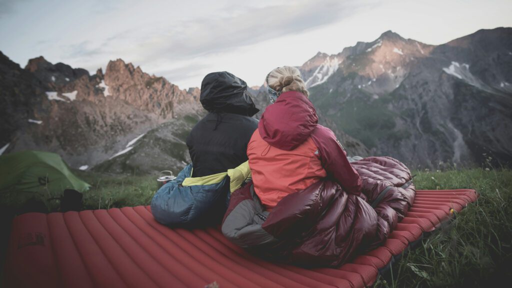 Two people enjoying the natural scenery while sitting on a sleeping pad