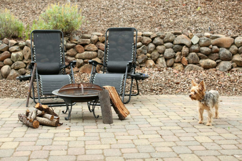 A fire pit next to two camping chairs