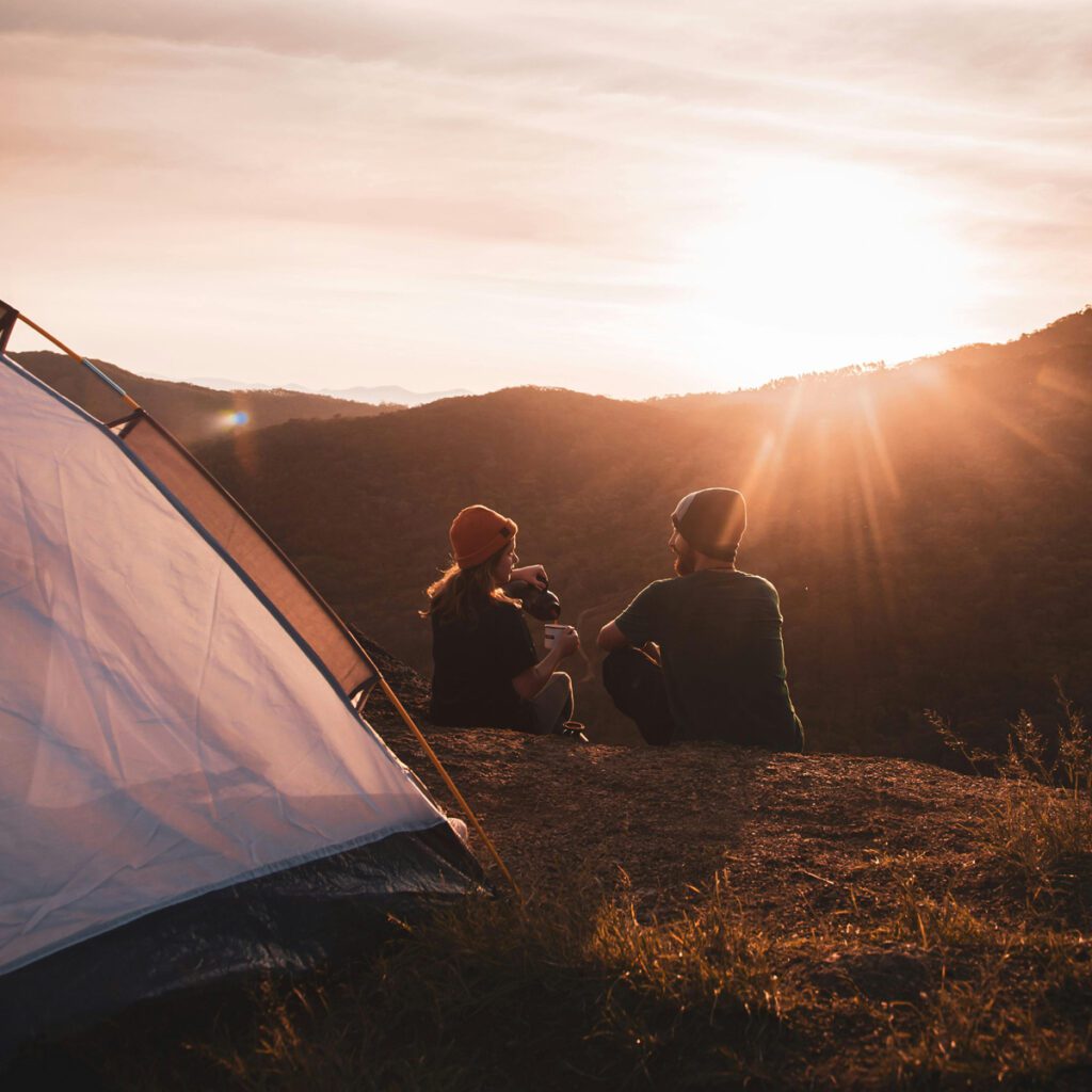A couple sitting close to their tent during sunrise