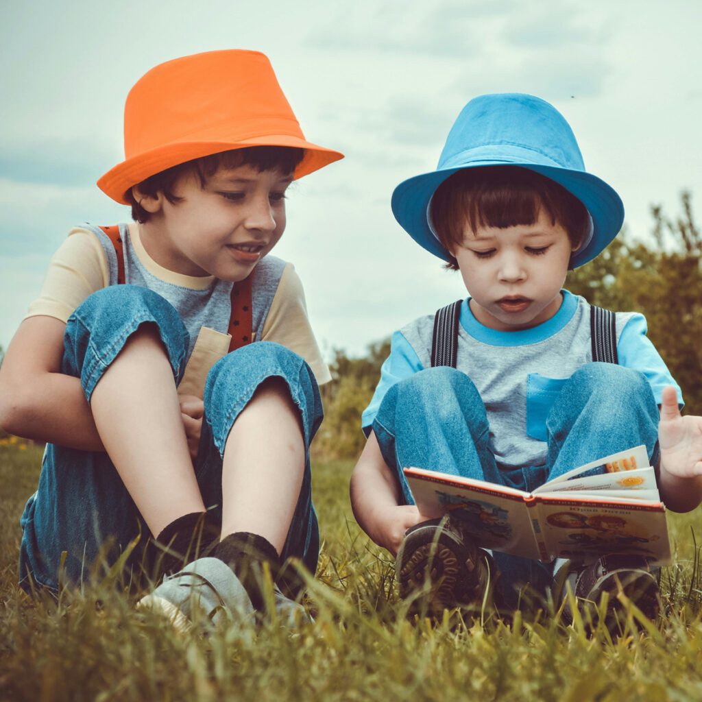 Two kids reading a book while outdoors